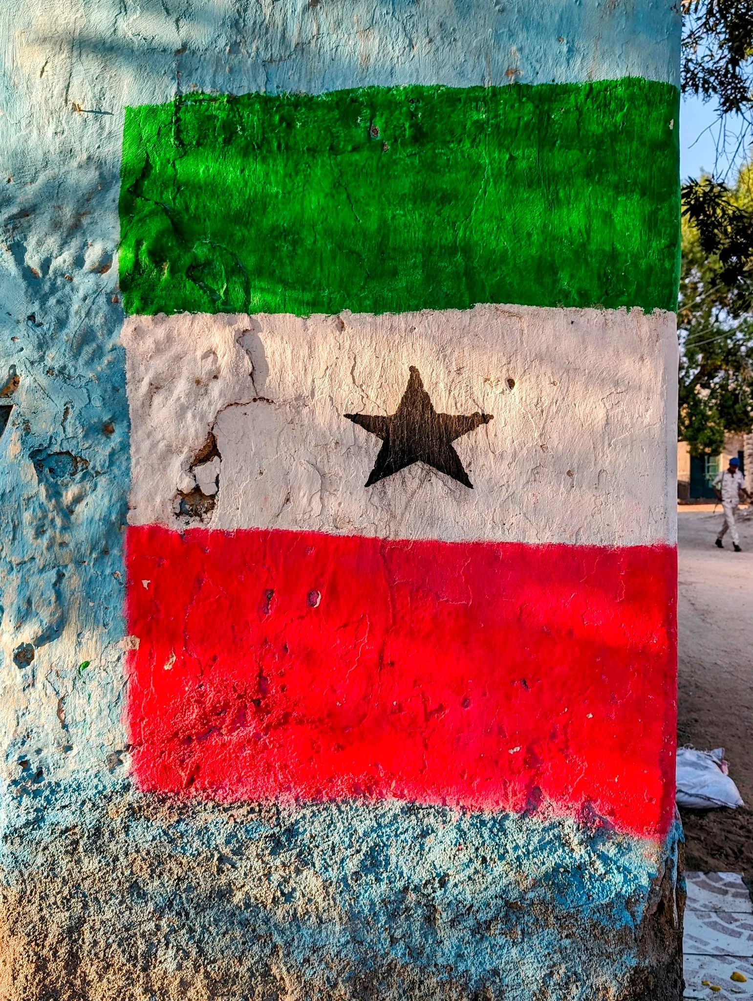 Somaliland flag painted on concrete pillar with green, white and red stripes and central black star.