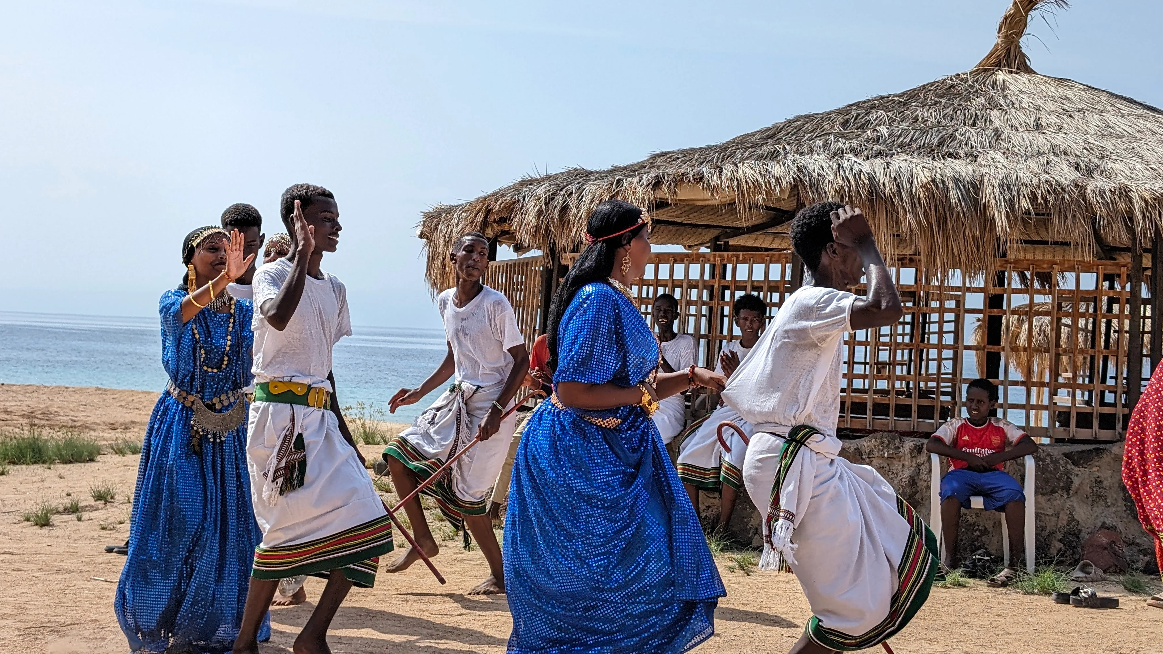 Traditional dancers in colorful dress perform on seaside pavilion during Horn of Africa tour.