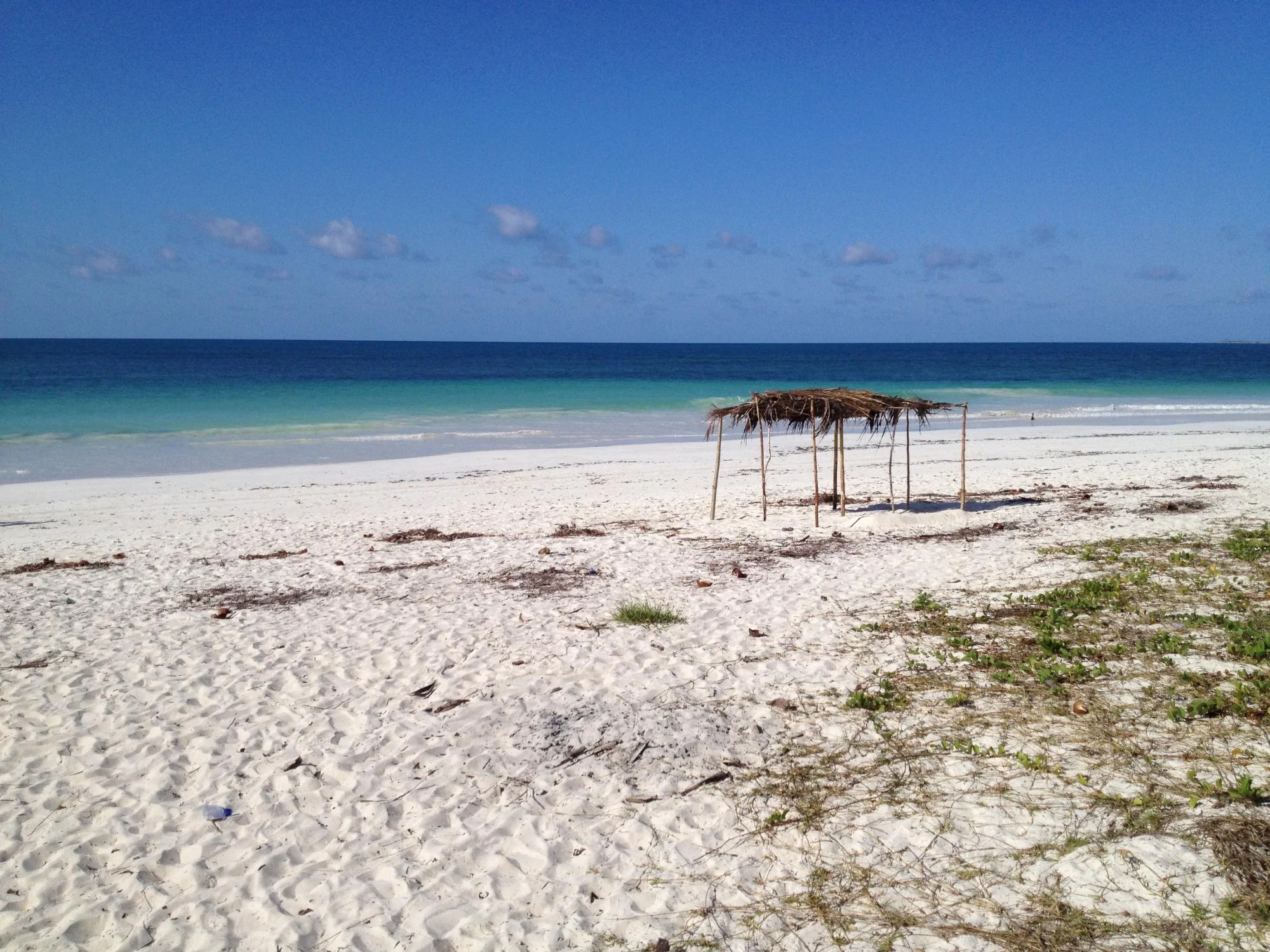 Pristine deserted white sand beach with a simple thatched palm shelter and turquoise Indian Ocean, Mozambique