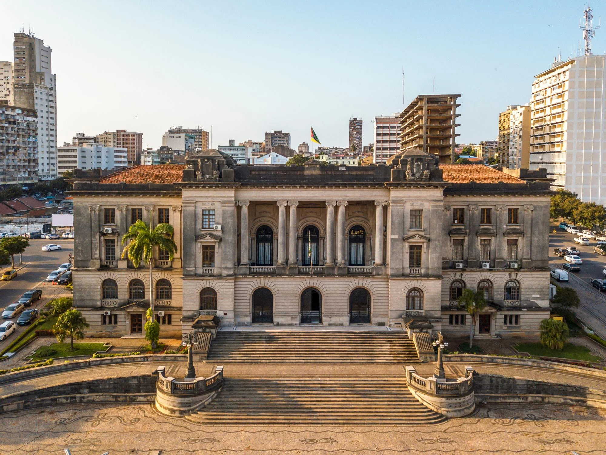 Aerial view of Maputo's neoclassical City Hall with stone columns and Mozambican flag amid the city skyline