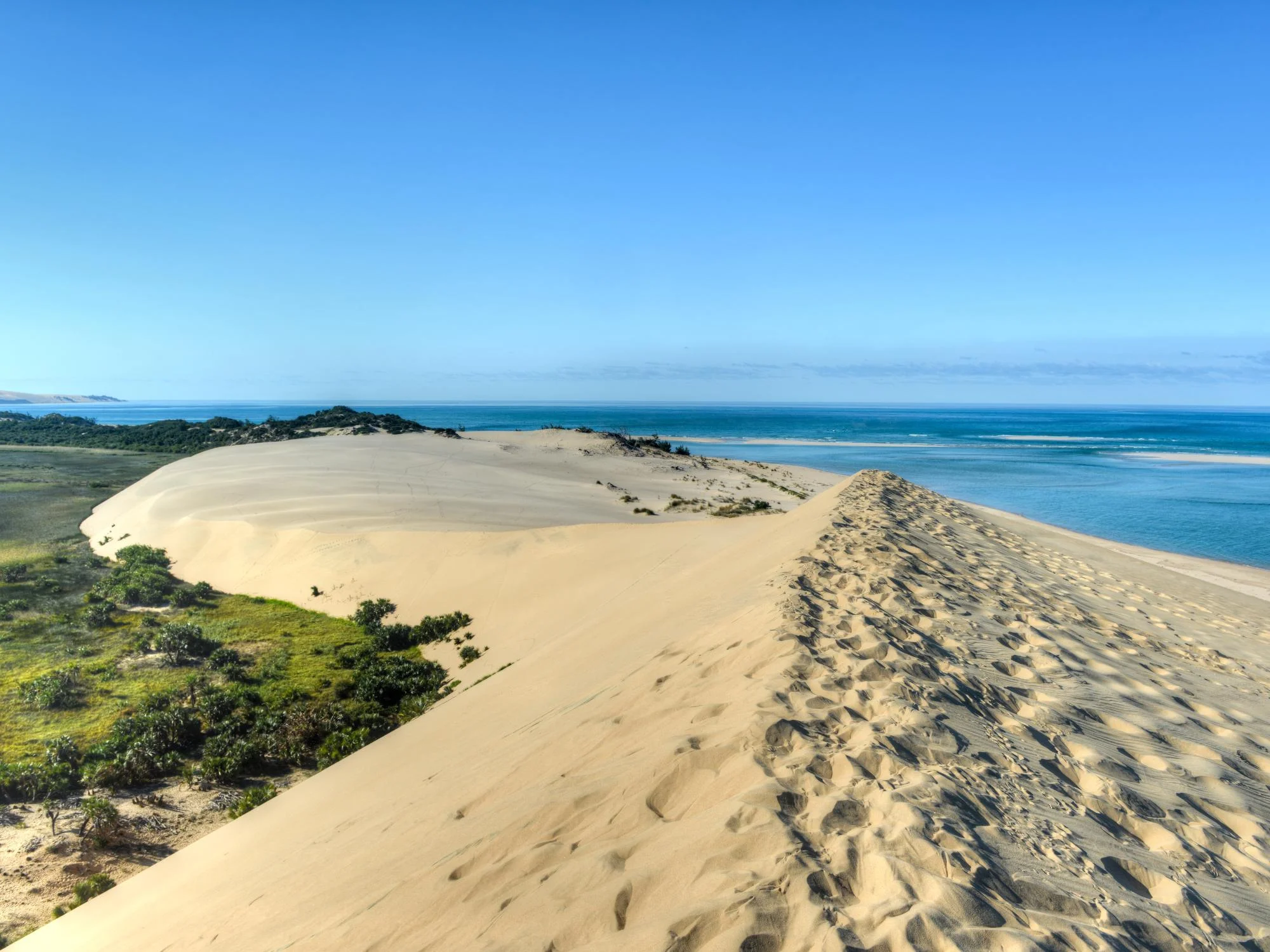 Sweeping coastal sand dunes descending to a turquoise Indian Ocean lagoon, Mozambique