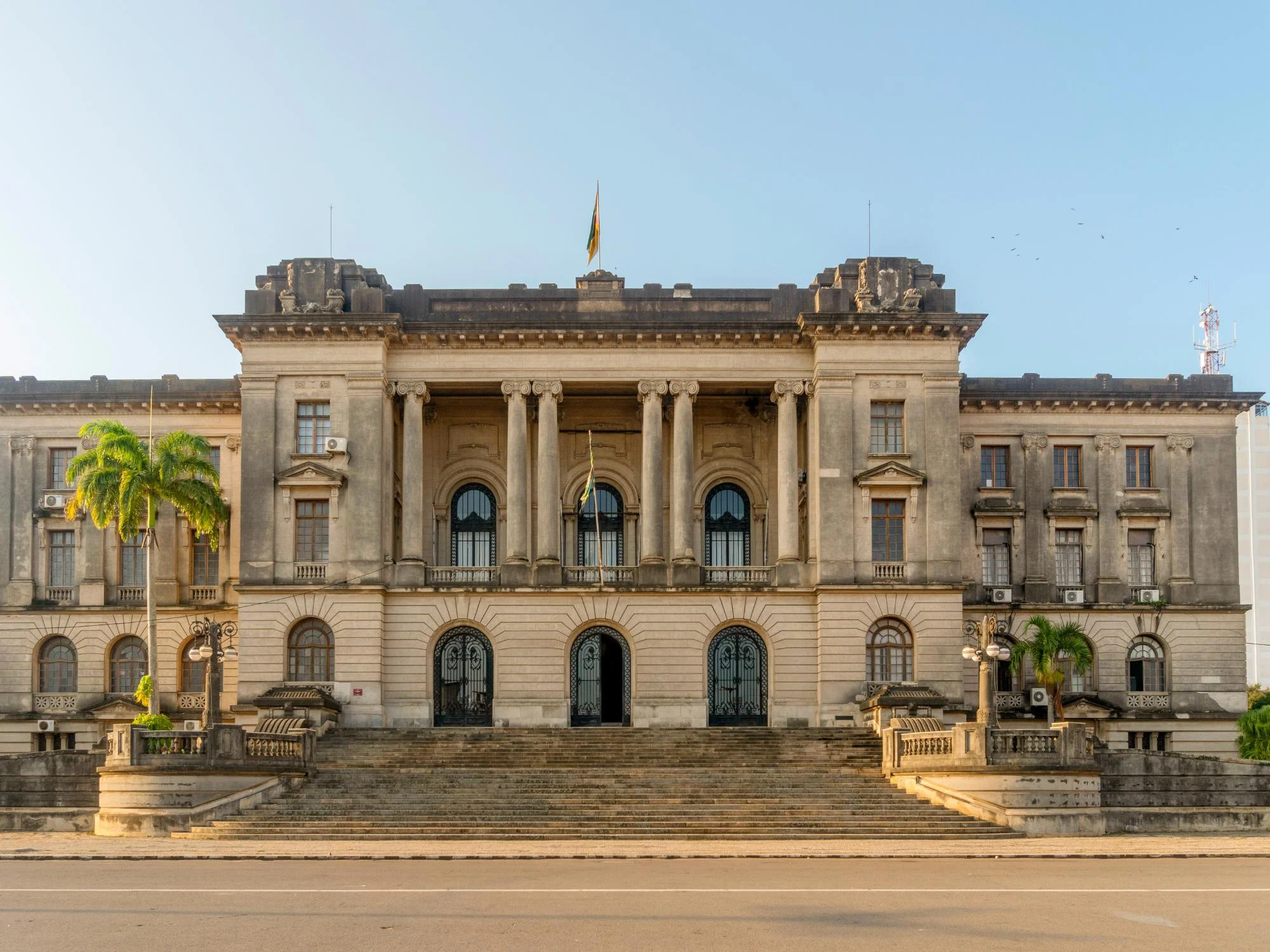 Grand neoclassical Portuguese colonial building with stone columns and the Mozambican flag, Maputo