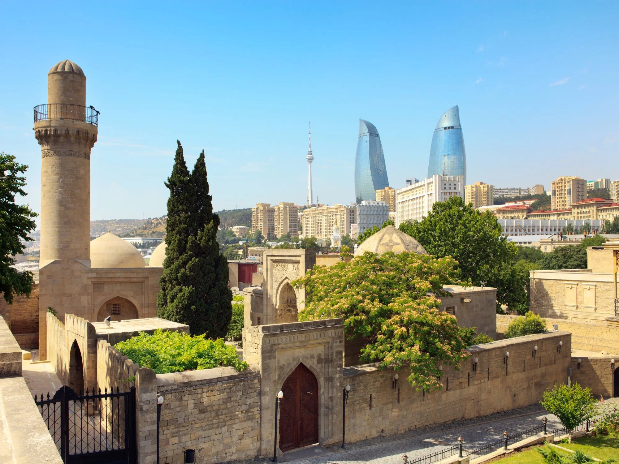 Stone watchtower and walled tomb complex of Baku's Old City, with the Flame Towers and TV Tower in the distance