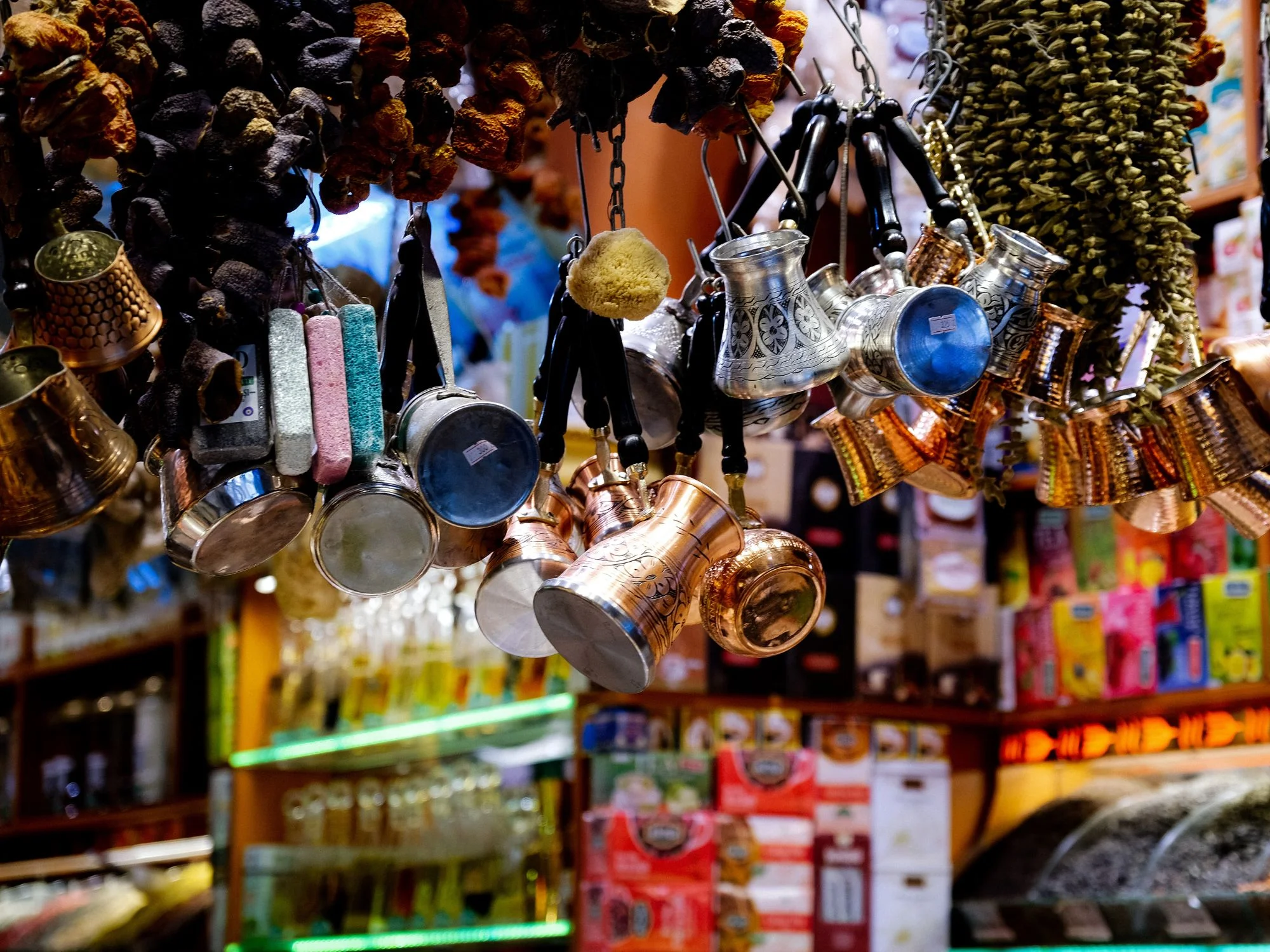 Azerbaijani bazaar display of hanging metal coffee pots, brass cups, and racks of dried fruits and nuts