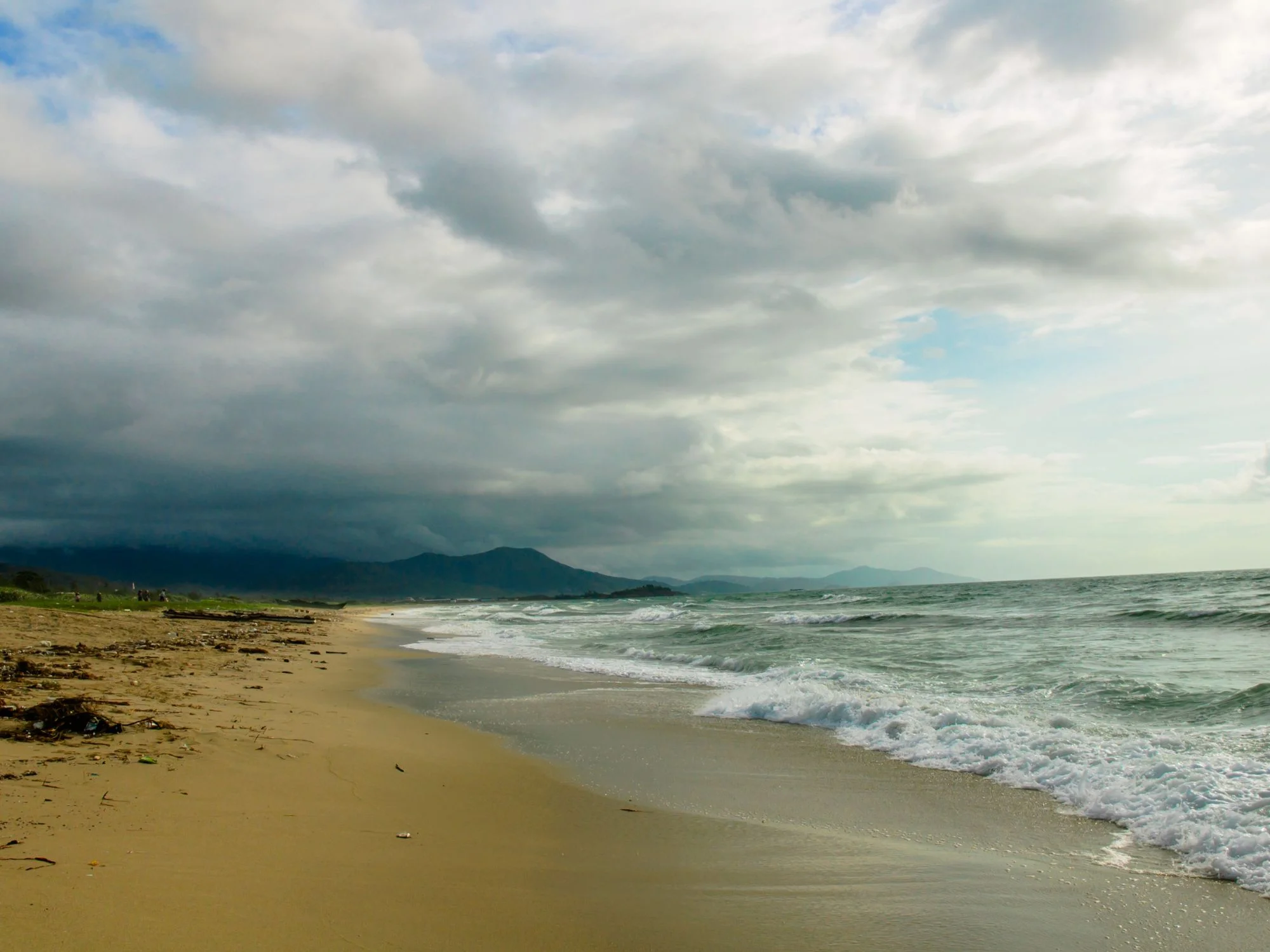 Stormy day on a Black Sea beach with dramatic dark clouds rolling above grey waves and wet sand