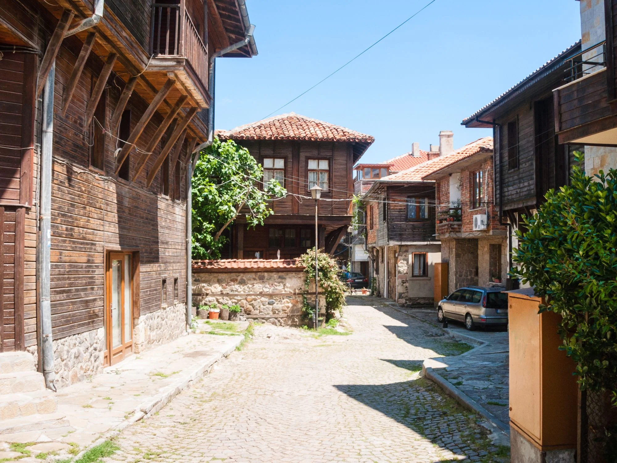 Cobbled lane through a traditional Black Sea wooden-architecture town with stone ground floors
