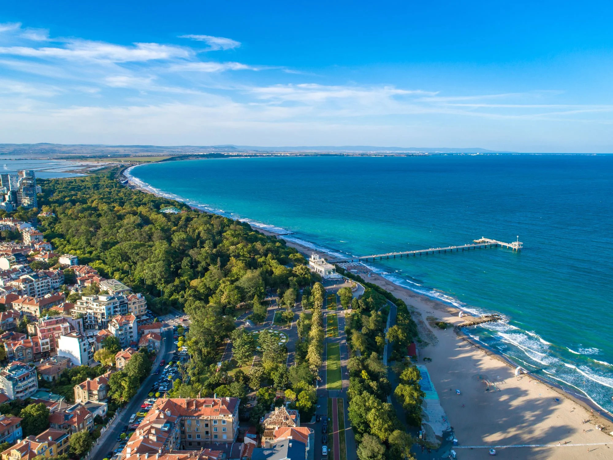 Aerial view of a long curving Black Sea beach with green forest meeting turquoise water