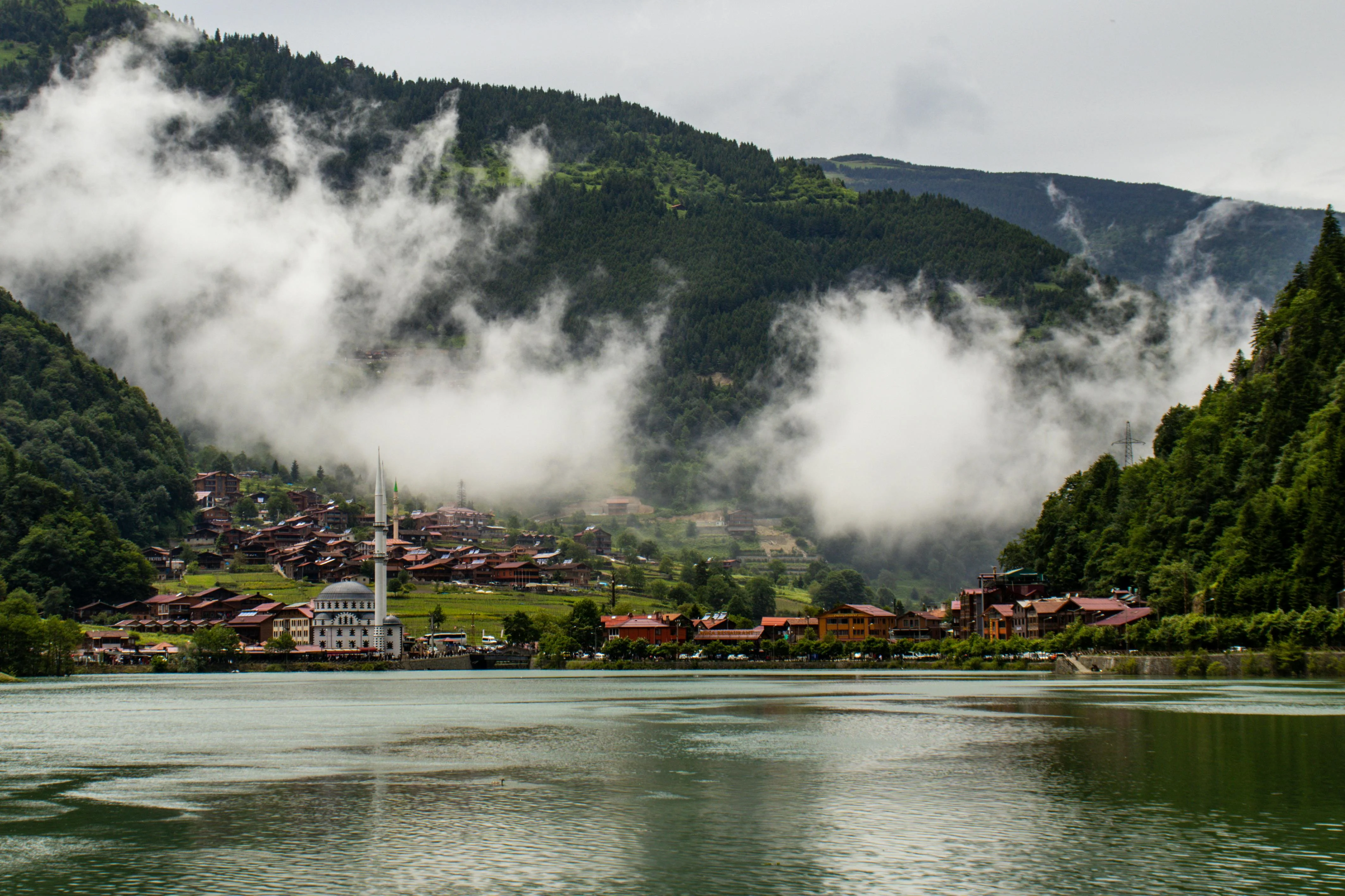 Uzungöl lake village in Turkey's Pontic Mountains, with a mosque and minaret reflected in misty water