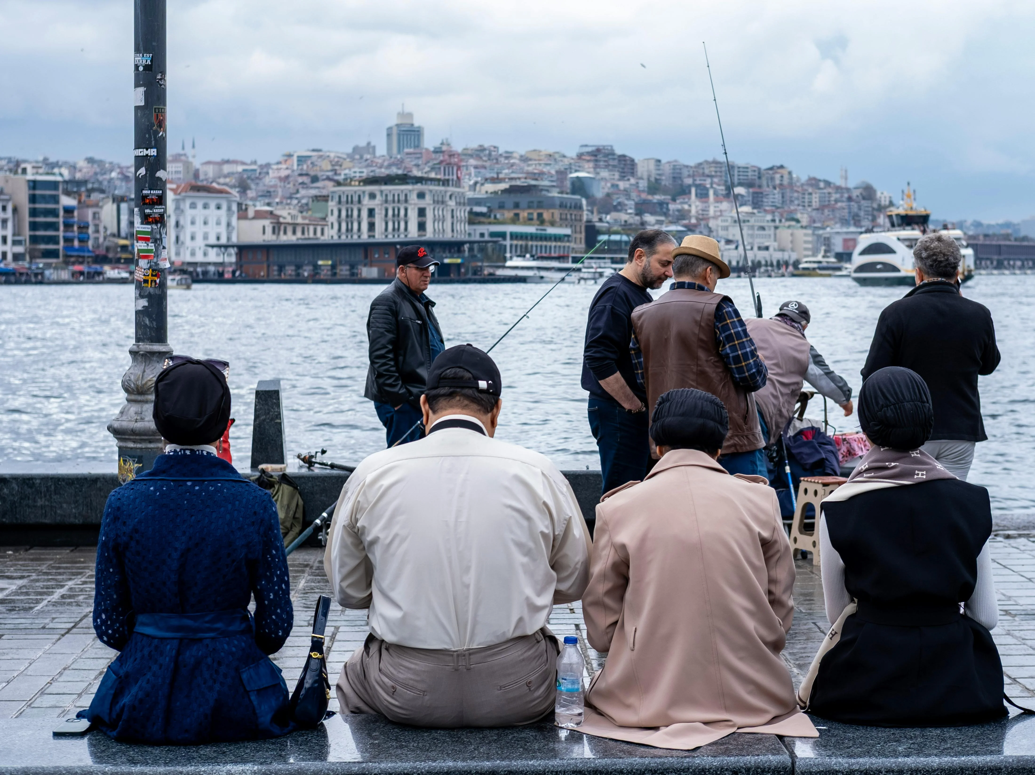 Locals fishing from the Galata Bridge in Istanbul, with the city skyline and Bosphorus ferries beyond