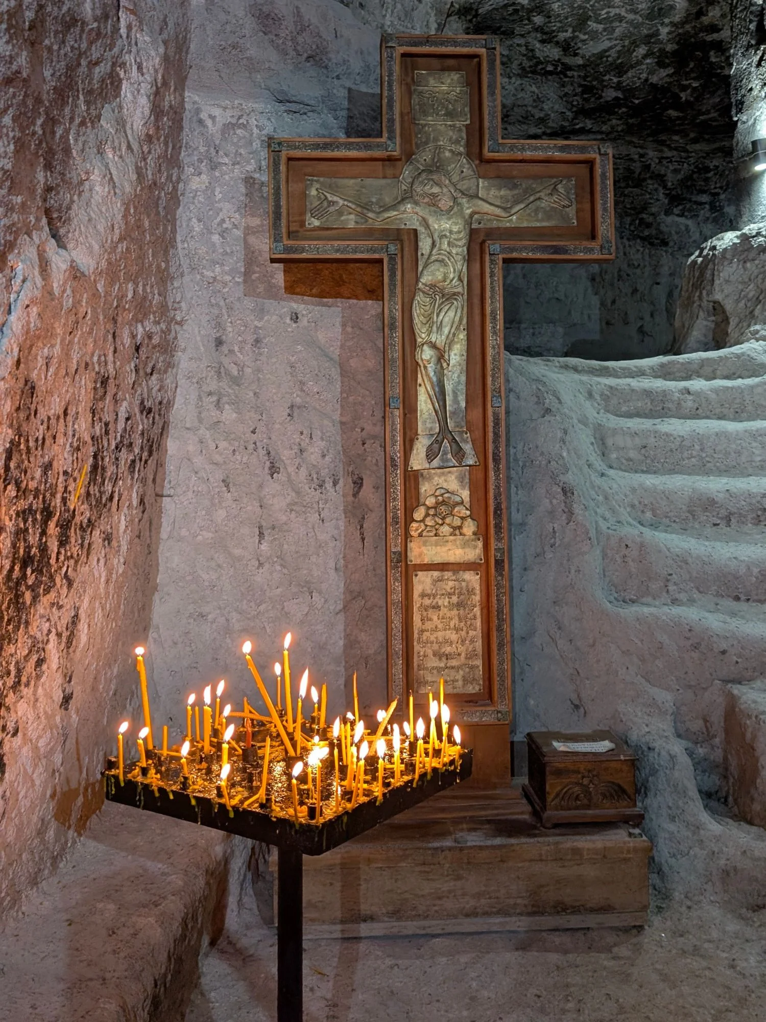 Glowing candles lit before icons inside a Georgian Orthodox cave-cut chapel