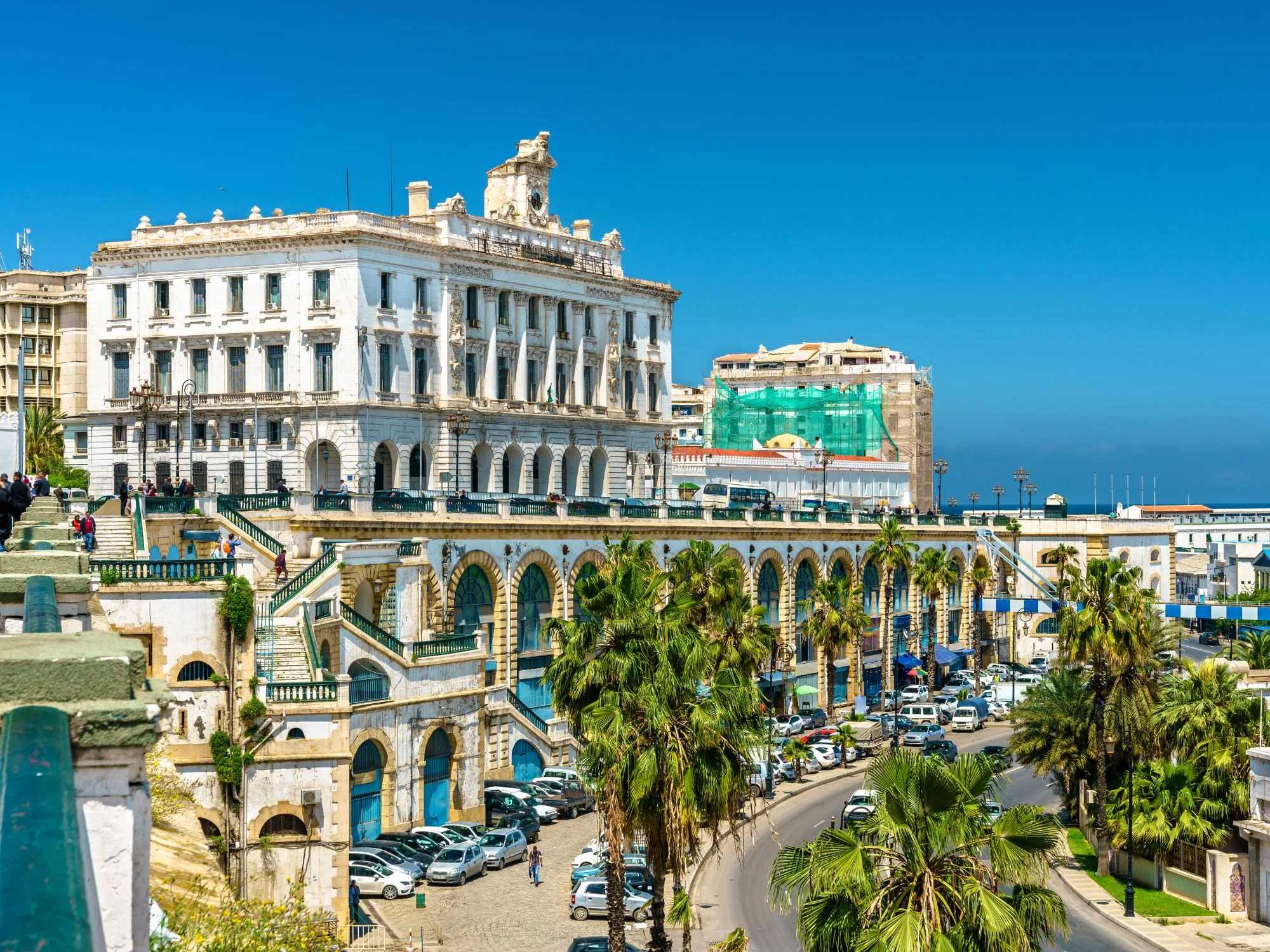 Historic French-colonial arcaded waterfront buildings in central Algiers framed by palm trees