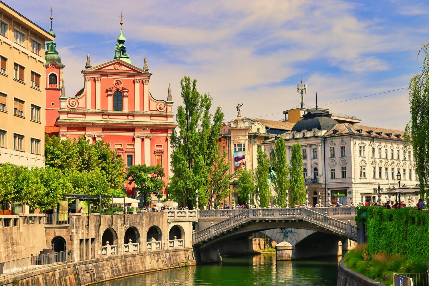 Pink Franciscan Church and a stone bridge over the Ljubljanica River in Ljubljana's Old Town, Slovenia