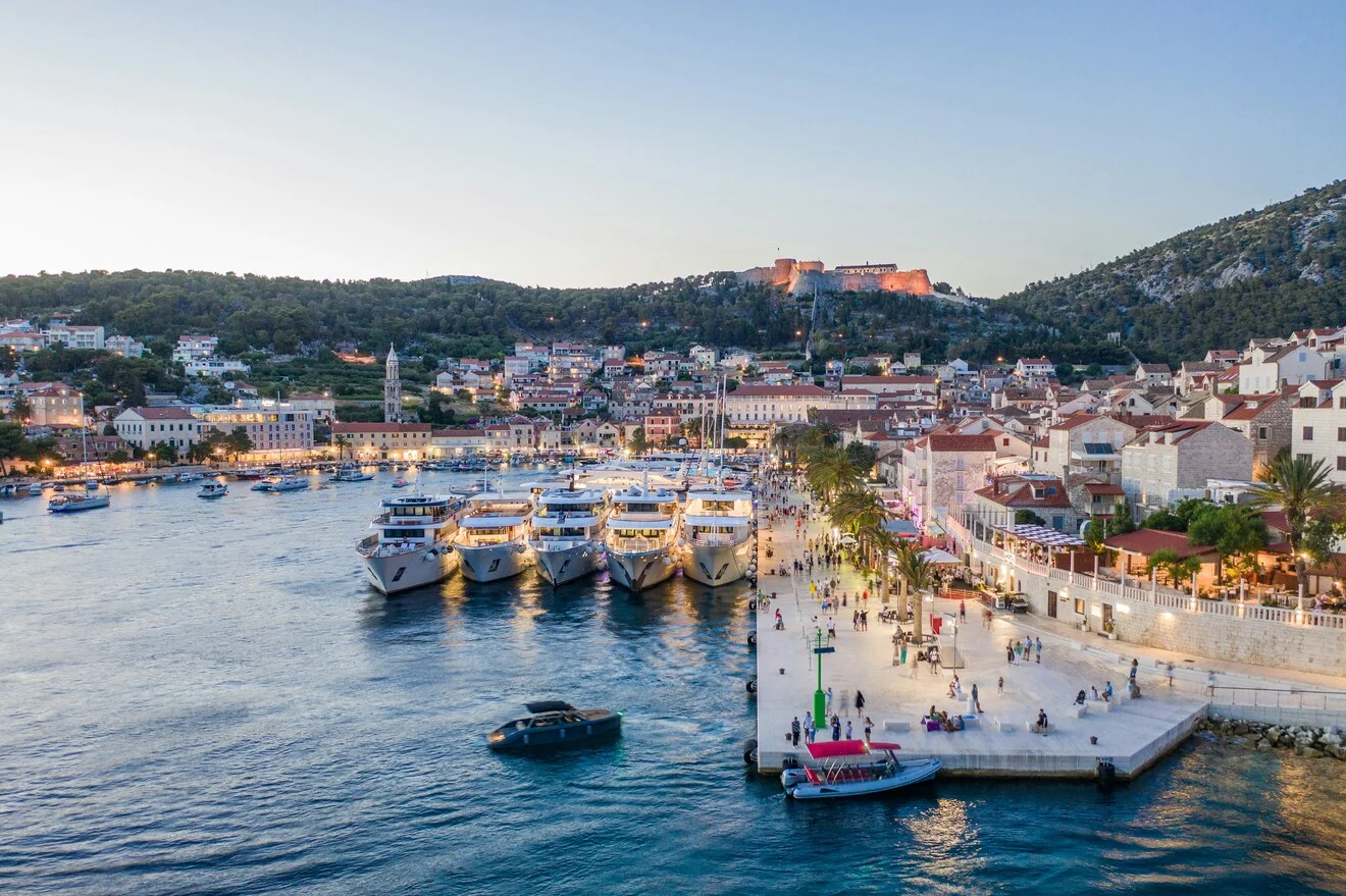 Aerial view at dusk of yachts moored along Hvar's old town promenade with the Spanish Fortress above, Croatia