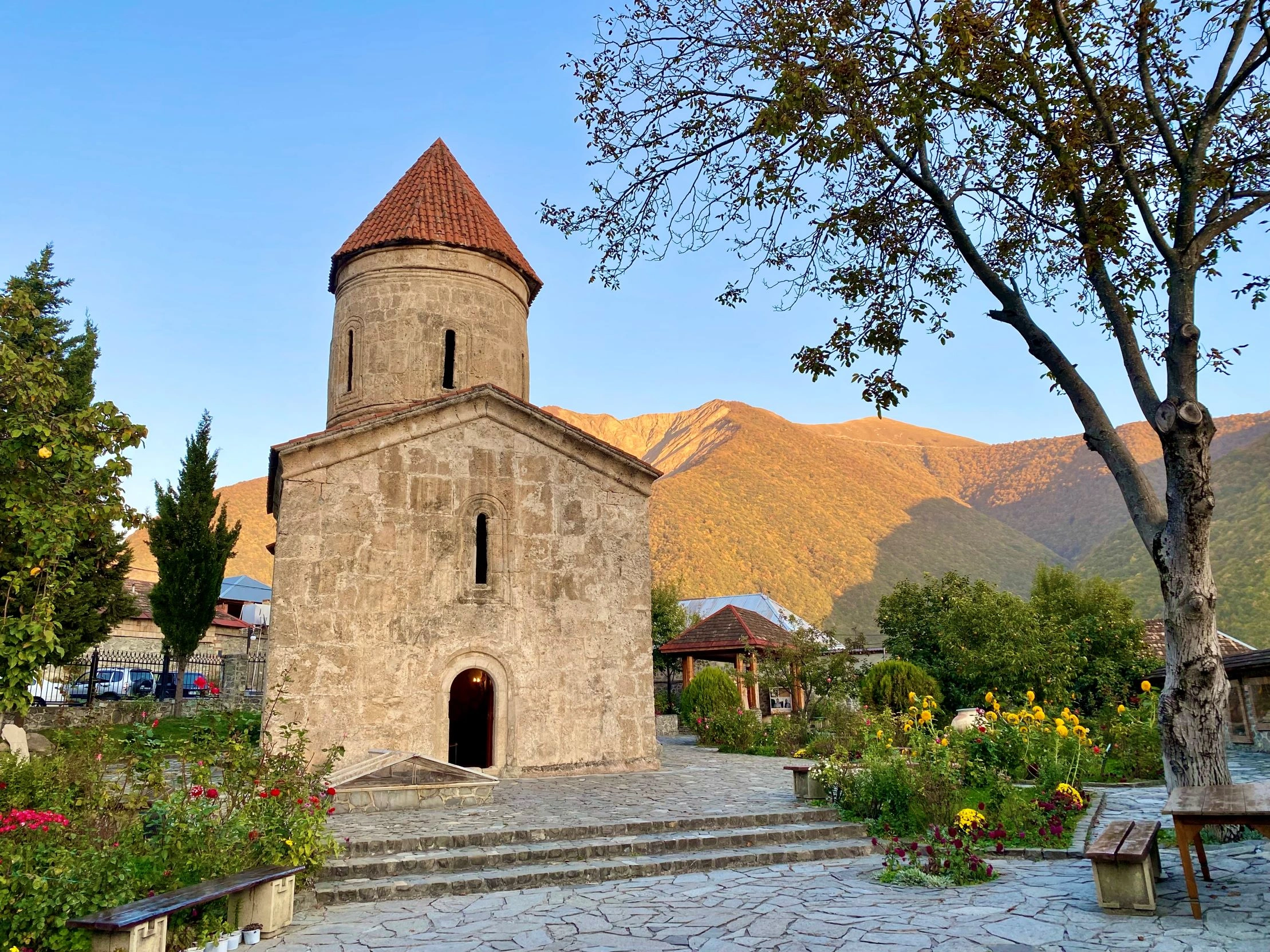 Ancient stone Albanian church with red-tiled cupola in Kish village at sunset, near Sheki, Azerbaijan