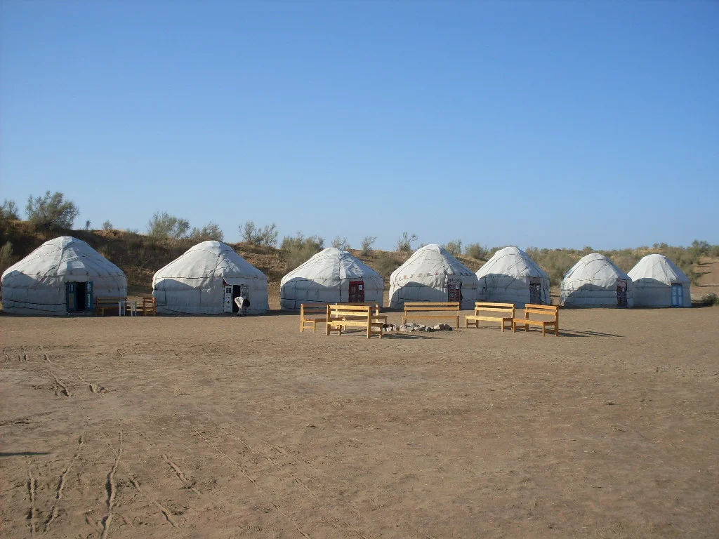 Cluster of white nomadic yurts on a sandy plain at the edge of the Kyzylkum Desert, Uzbekistan