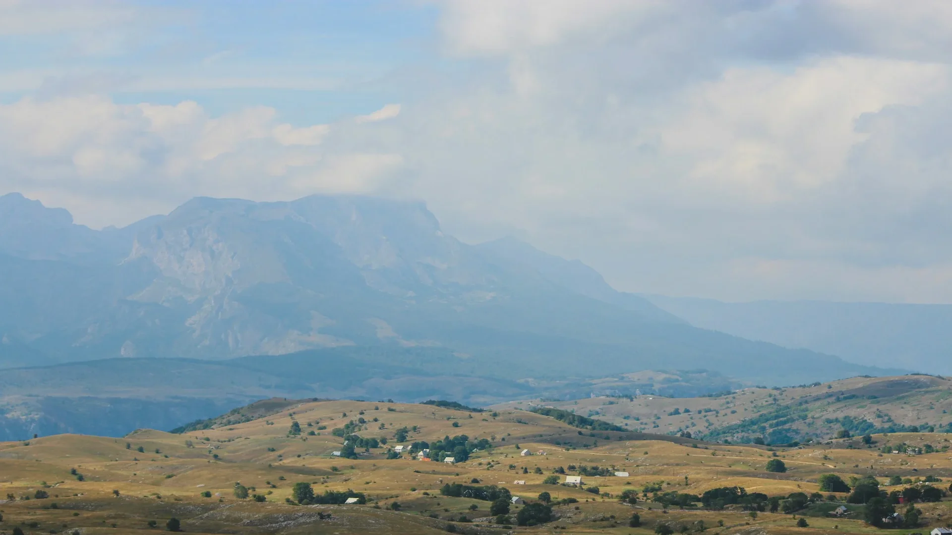 Hazy view of Durmitor's jagged limestone peaks rising above grassy karst plateaus, Montenegro