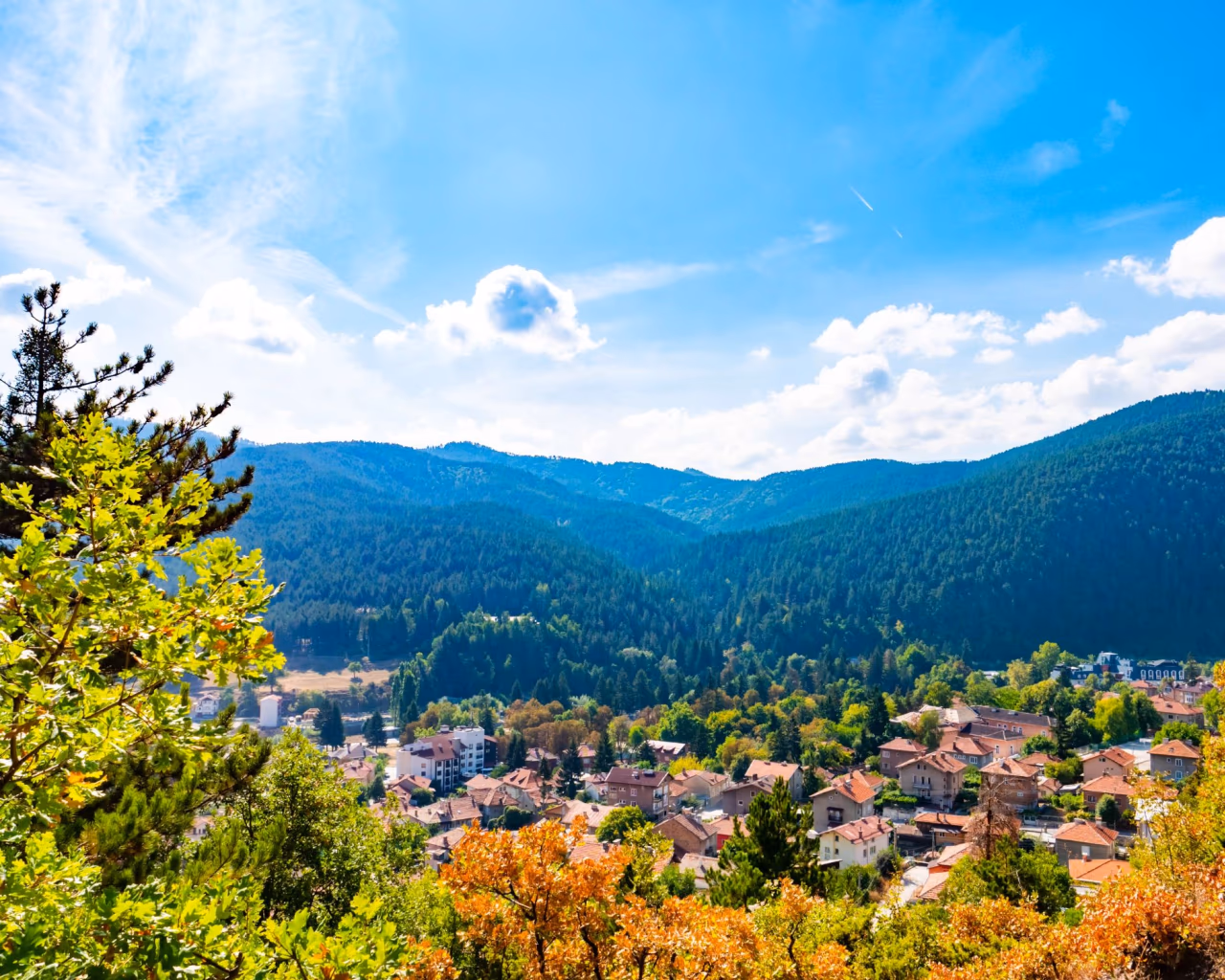 View over Bulgarian town surrounded by green mountains and blue sky in summer.