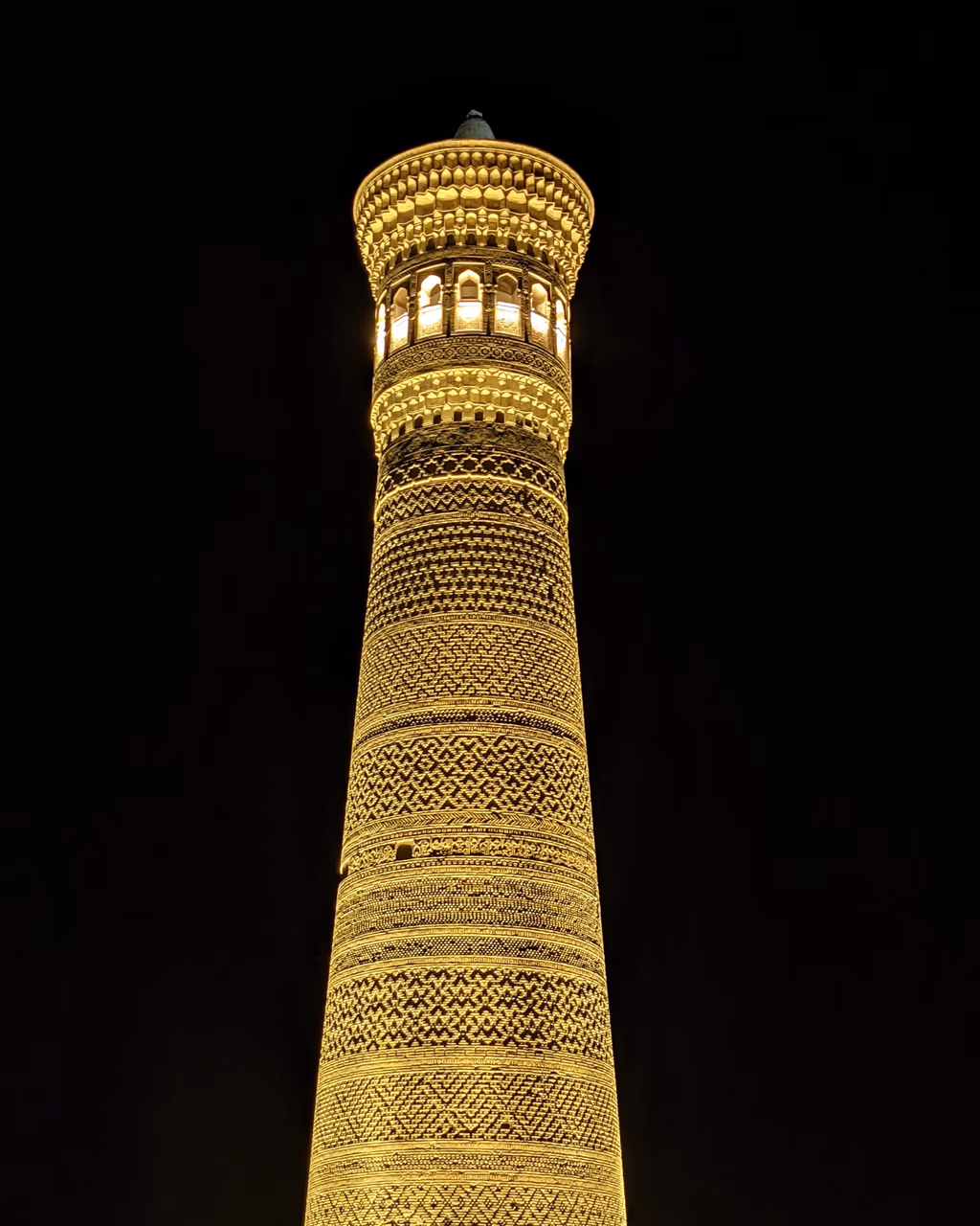 A glowing nighttime view of the historic Kalyan Minaret, an iconic symbol of Bukhara’s Silk Road past.