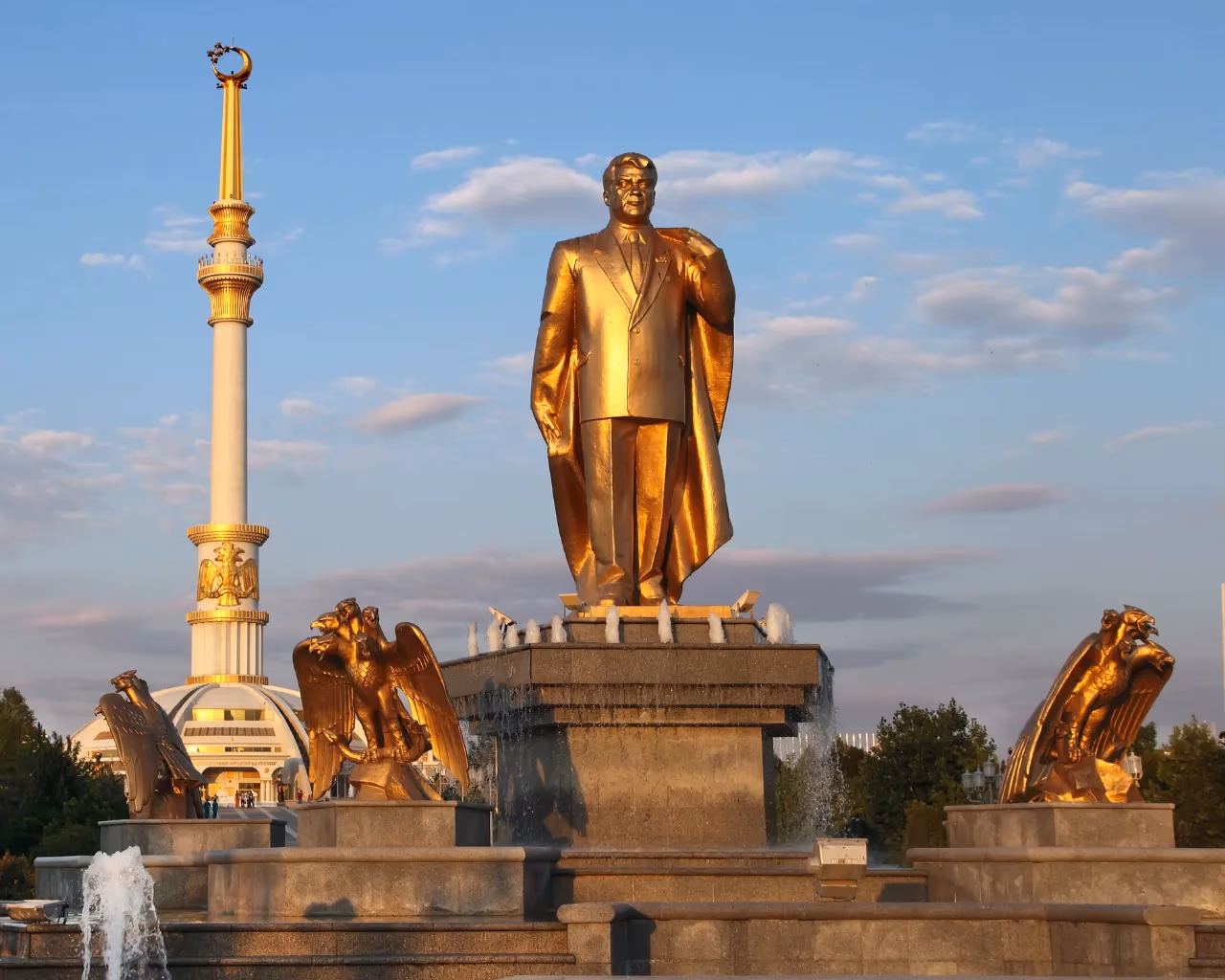 Golden statues of Niyazov and the Independence Arch glowing in Ashgabat, Turkmenistan.