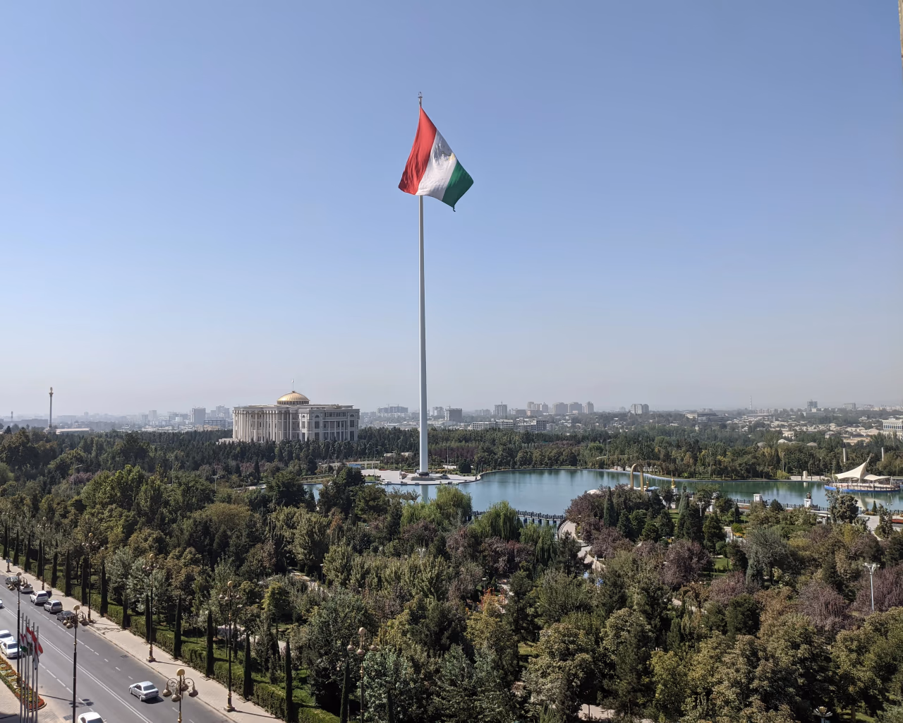 A panoramic city view featuring the Tajik flag and the grand palace, highlighting Dushanbe’s skyline.