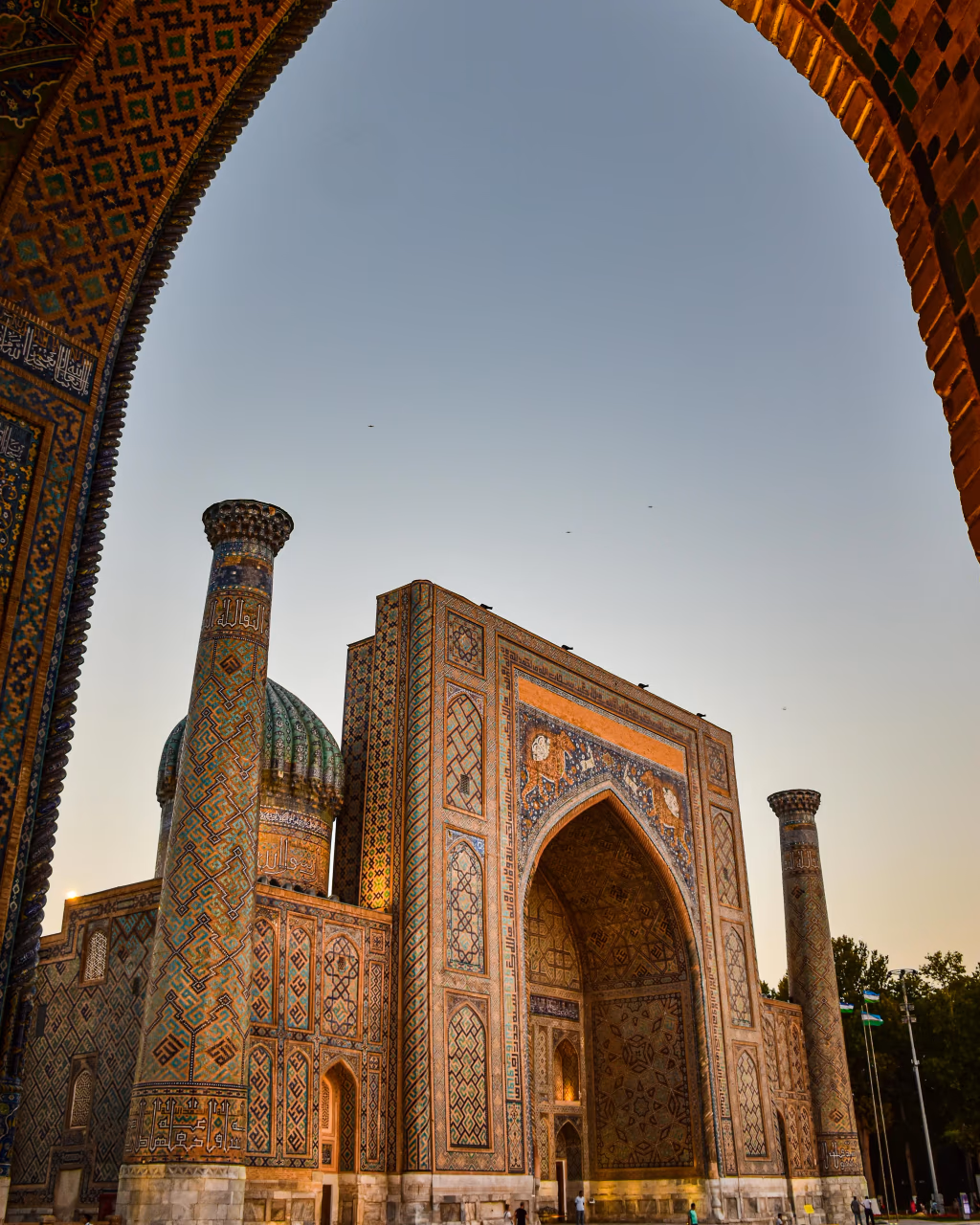 A stunning archway framing the intricate tilework of Registan Square, a jewel of Samarkand’s history.