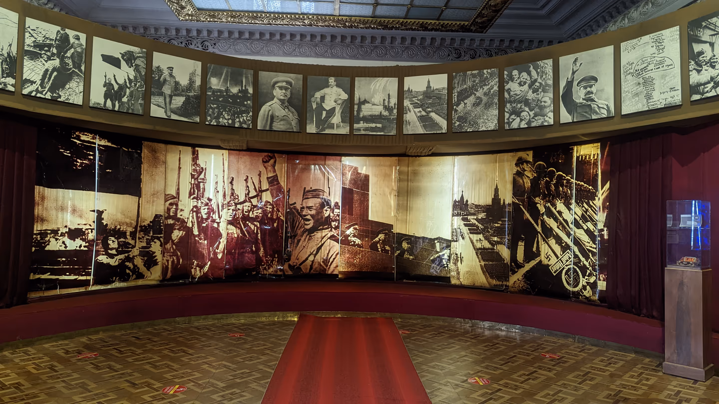 Soviet-era war exhibition inside the Stalin Museum in Gori, Georgia, featuring historical photos and propaganda murals.