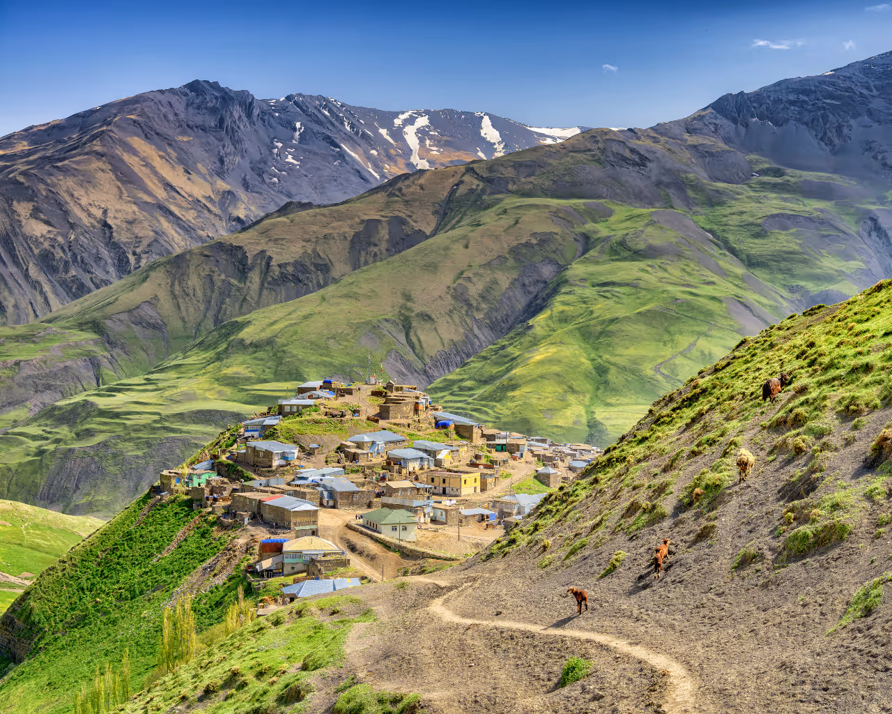 Aerial view of Khinaliq, Azerbaijan, a remote mountain village surrounded by rolling green hills and rugged landscapes.