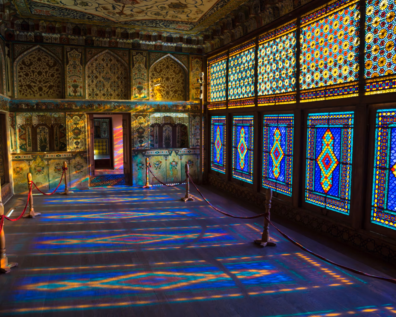 Interior of Sheki Khan’s Palace in Azerbaijan with colorful stained glass windows and ornate floral wall paintings