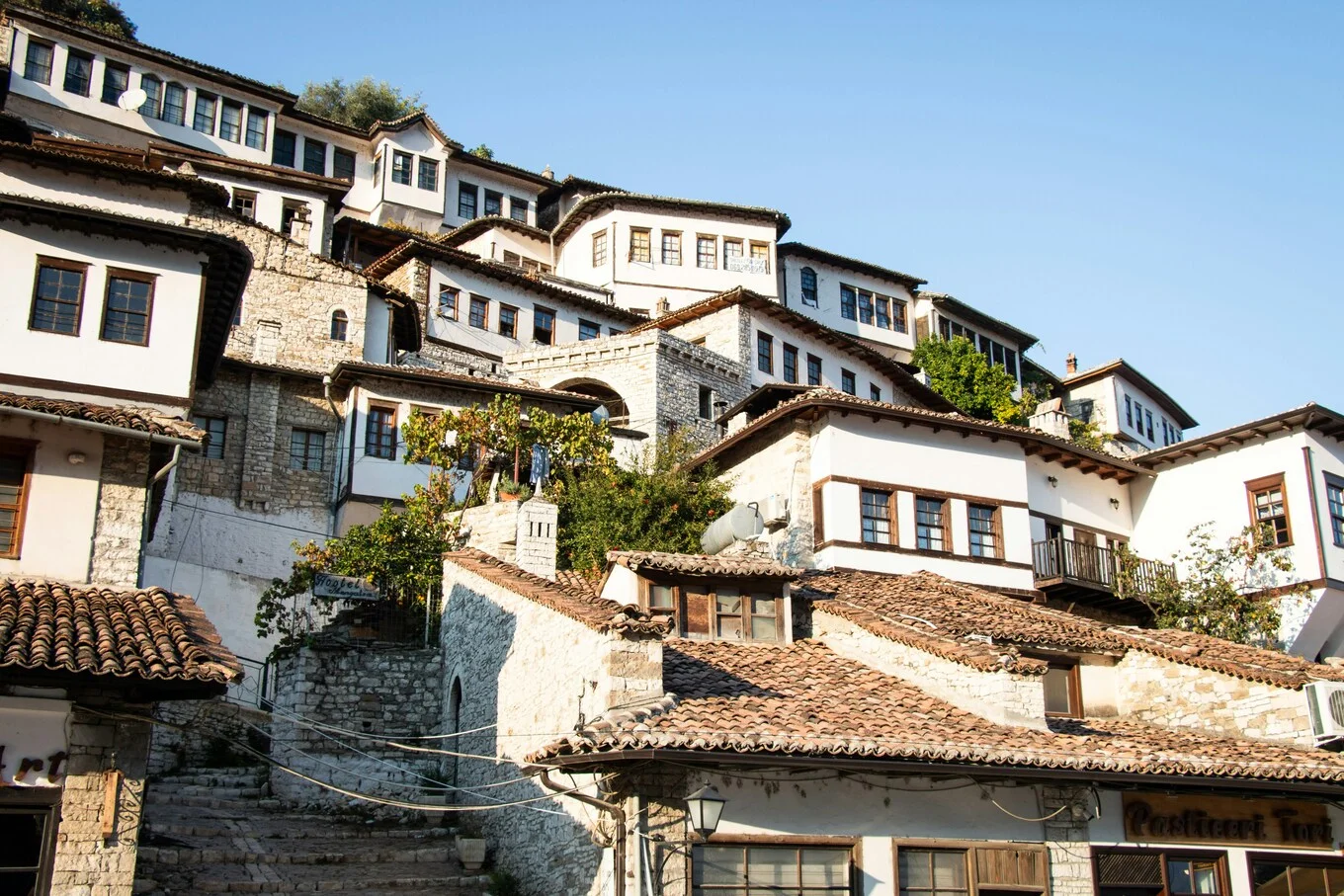 Close-up view of Berat’s historic Ottoman houses, stone stairways, tiled rooftops, and white façades in the old town of Albania’s City of a Thousand Windows.