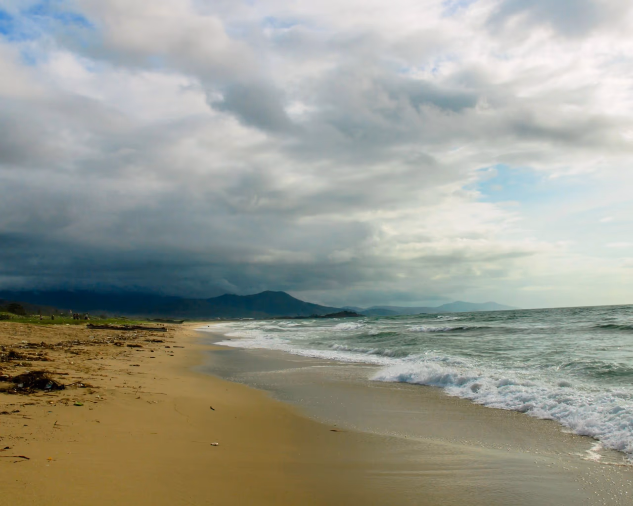 Stormy day on a Black Sea beach with dramatic dark clouds rolling above grey waves and wet sand
