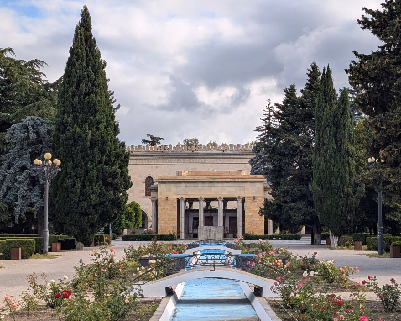 Symmetrical reflecting pool with cascading steps and cypress alley leading to a stone colonnaded building