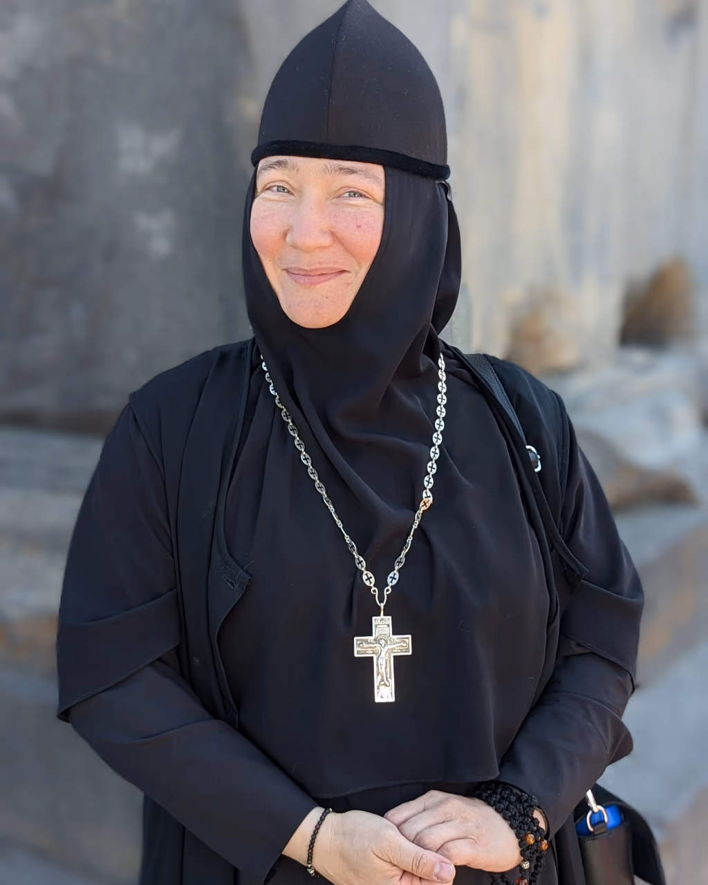 Armenian nun portrait – smiling nun in black habit with a silver cross necklace at a convent in Armenia.