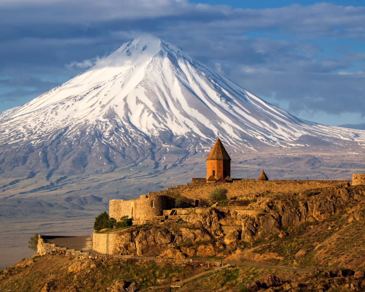 Caucasus Explorer tour – snow‑capped Mount Ararat towering over the hilltop Khor Virap monastery in Armenia’s Ararat Valley.