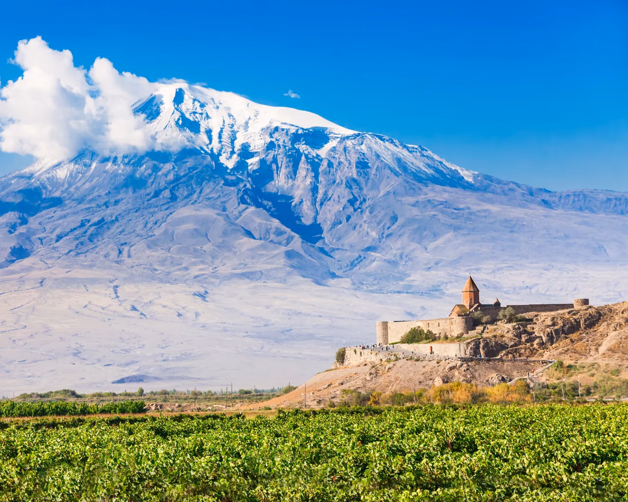Khor Virap vineyards – Khor Virap monastery perched on a rocky hill above lush vineyards with Mount Ararat dominating the skyline.