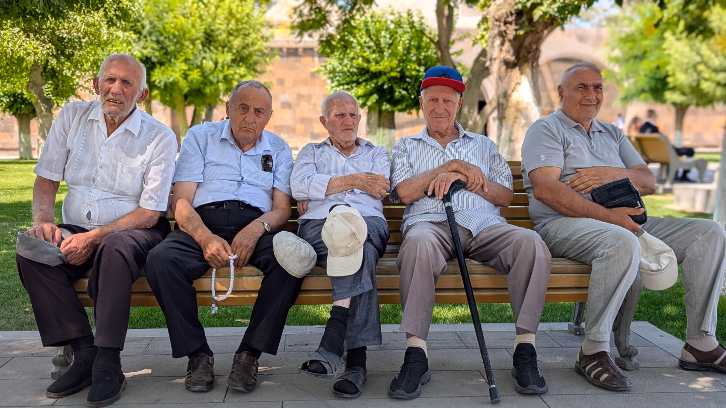 Elderly Armenian men – five elderly men in shirts and caps relaxing on a bench in a shaded park on a sunny day in Armenia.