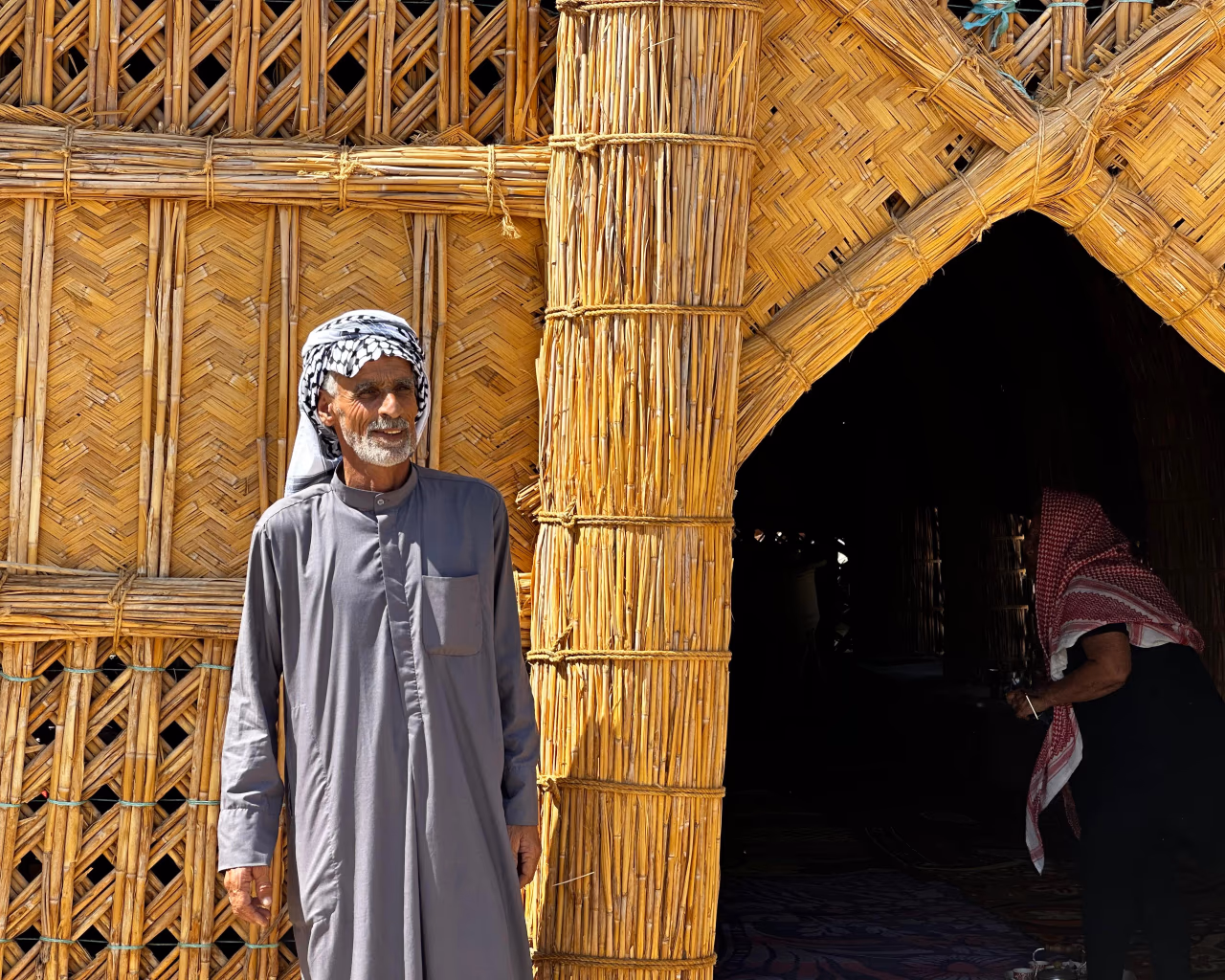 Elderly Marsh Arab man in traditional clothing outside a reed house in southern Iraq’s marshes