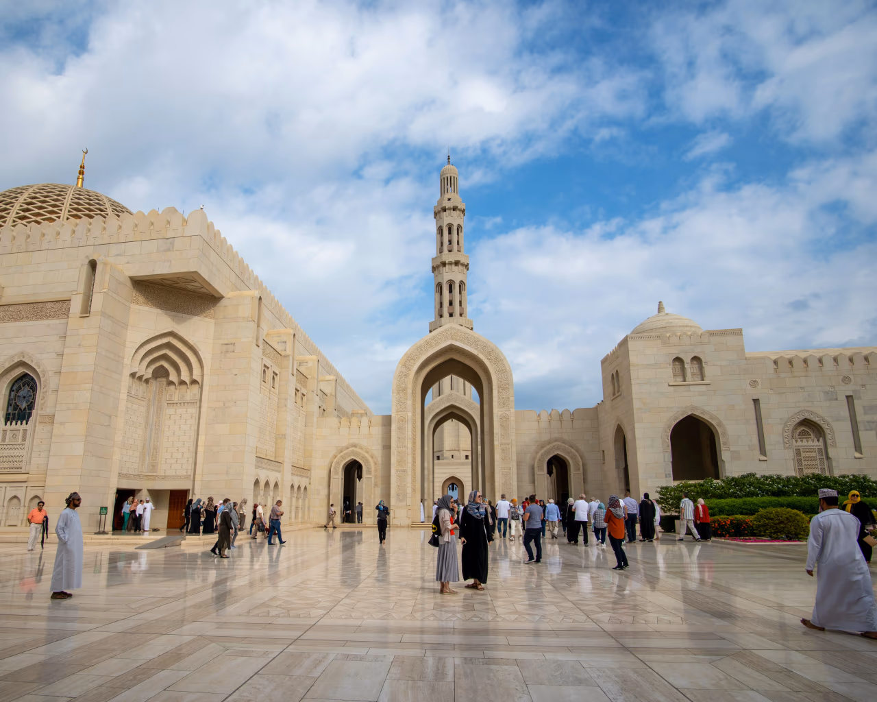Visitors exploring courtyard of Sultan Qaboos Grand Mosque on an Oman tour.