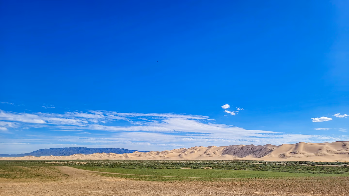 Mongolia sand dunes stretching under blue sky at Gobi Desert National Park.