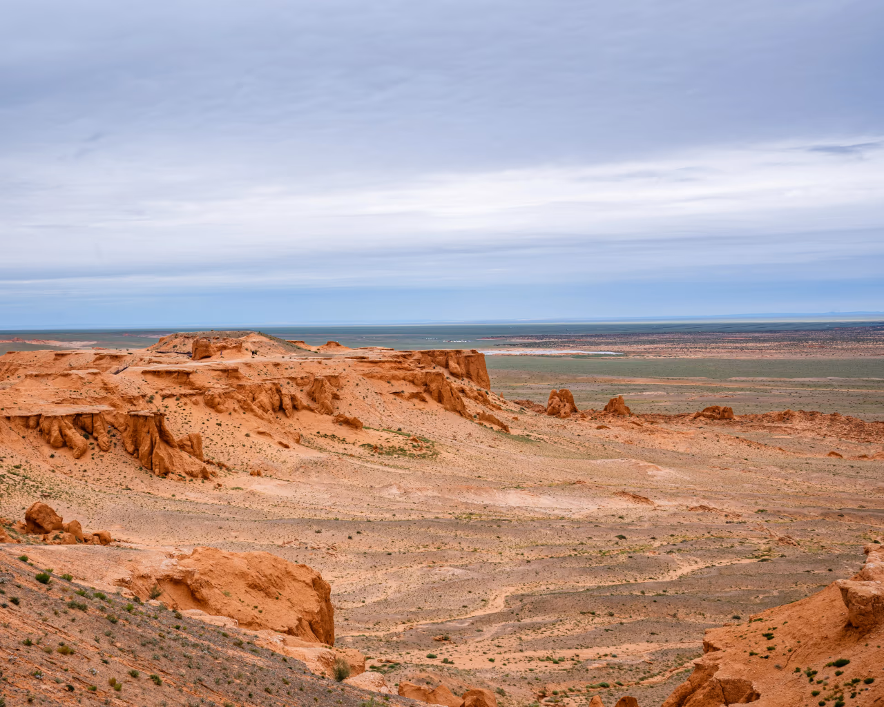Bayanzag Flaming Cliffs Mongolia red sandstone formations under cloudy sky panoramic view.