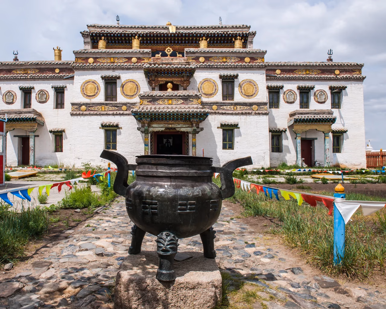 Erdenezuu Monastery Mongolia, ornate white building with bronze incense burner in front.