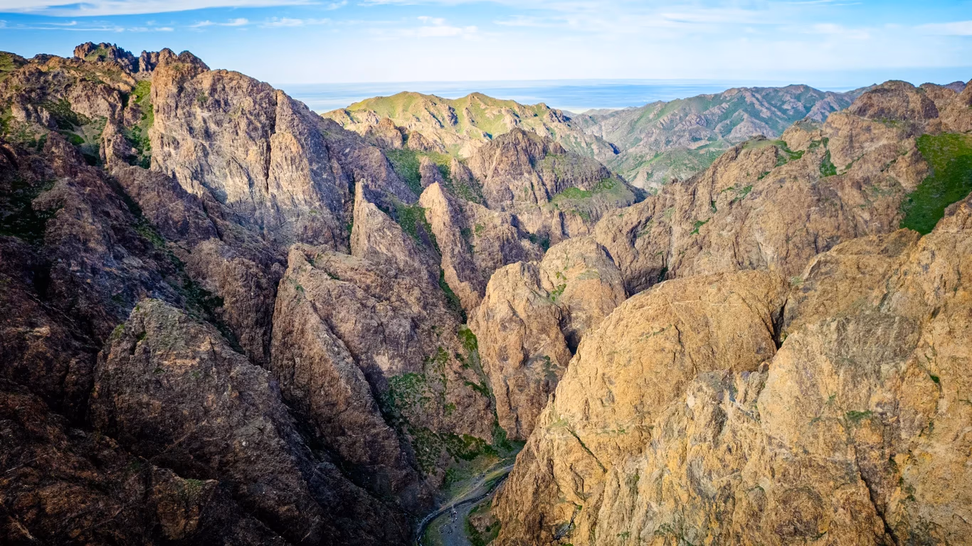 Yolyn Am Mongolia, dramatic rocky cliffs and green slopes seen from above.