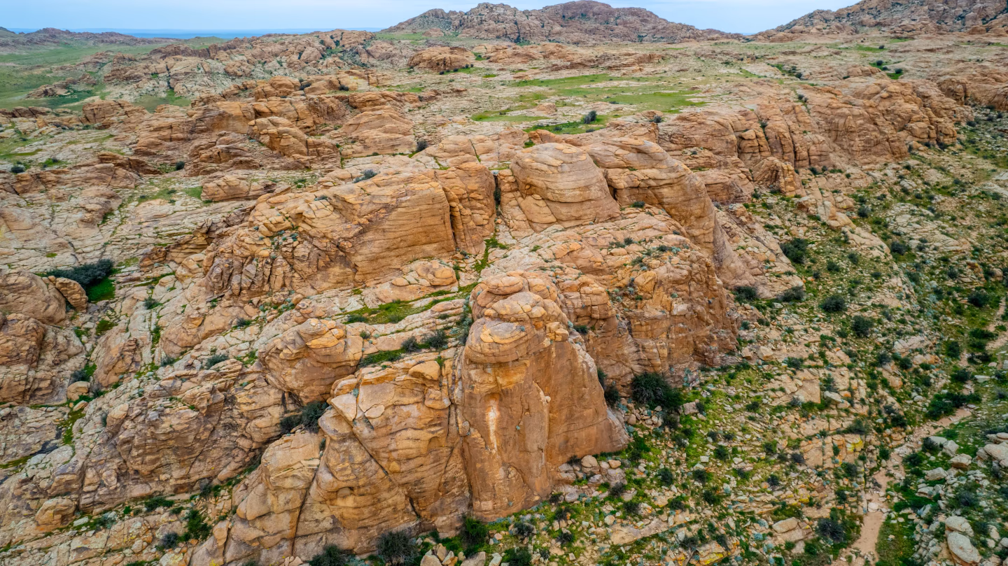 Rocky cliffs and green patches of Mongolia's Baga Gazriin Chuluu area.