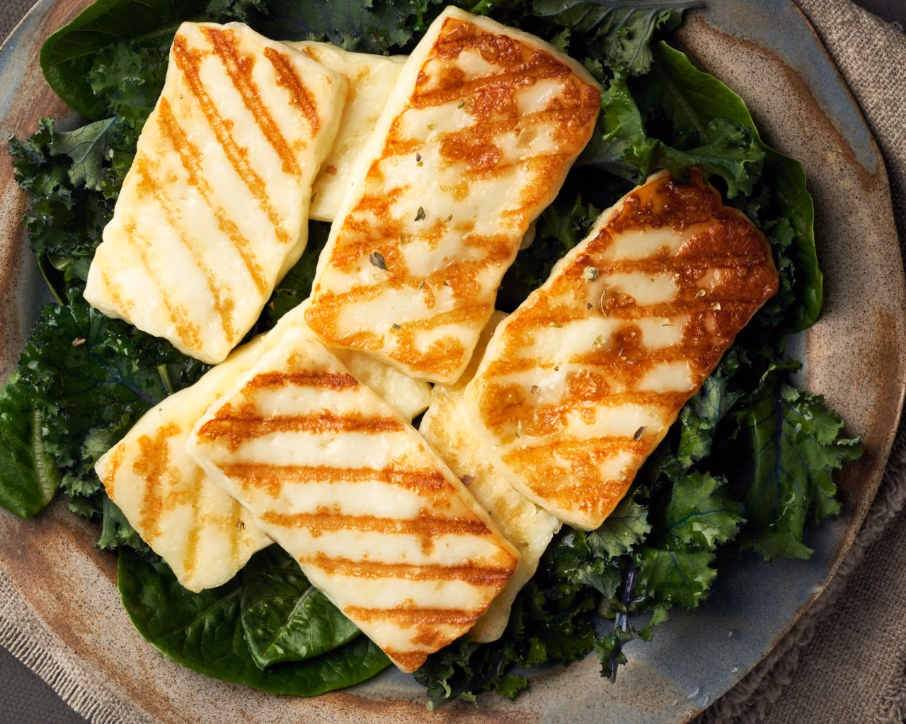 Grilled halloumi slices on a bed of fresh greens, traditional Cyprus cheese dish.