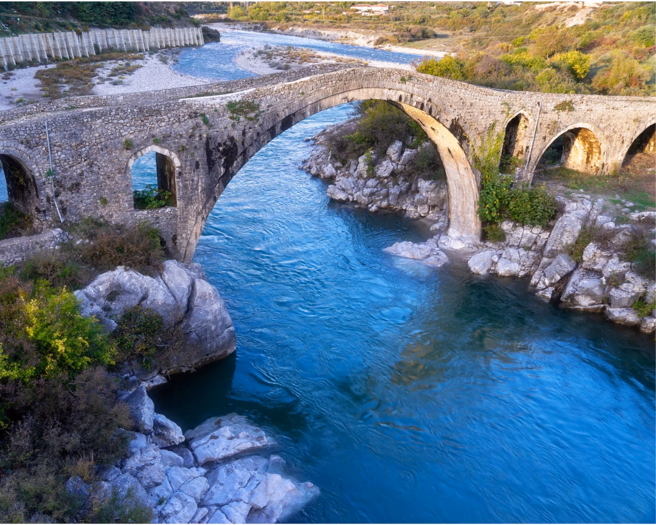Historic Mesi Bridge crossing the Kir River near Shkoder, Albania, surrounded by nature.