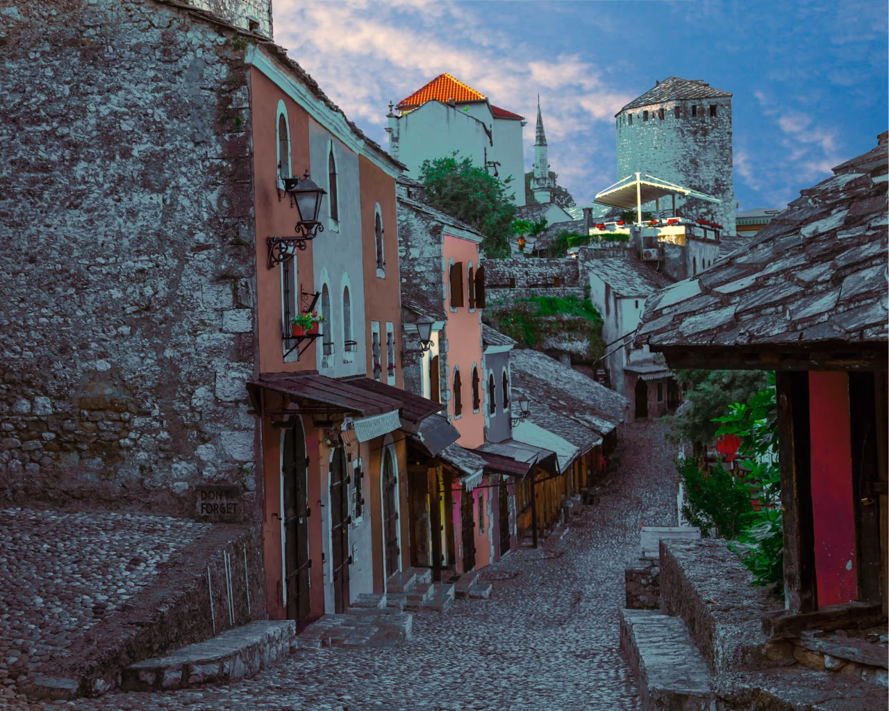 Cobblestone street lined with colorful houses and towers in Old Town Mostar, Bosnia and Herzegovina.