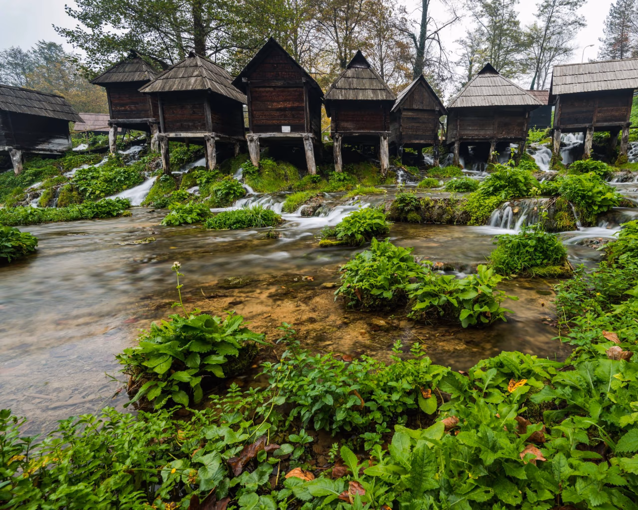 Charming wooden watermills sitting atop a rushing stream in lush greenery at Jajce, Bosnia and Herzegovina.