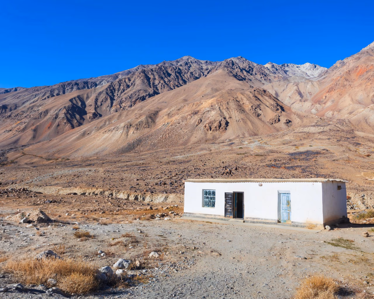 Isolated white roadside building in a rocky, barren mountain landscape near Murghab.