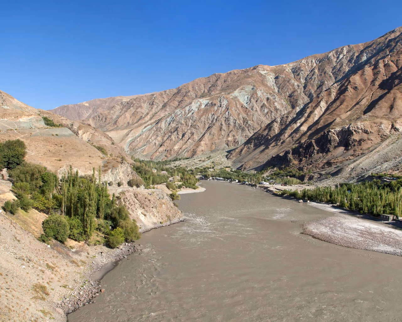 Panj River flowing between steep mountain slopes along the scenic Pamir Highway in Tajikistan.
