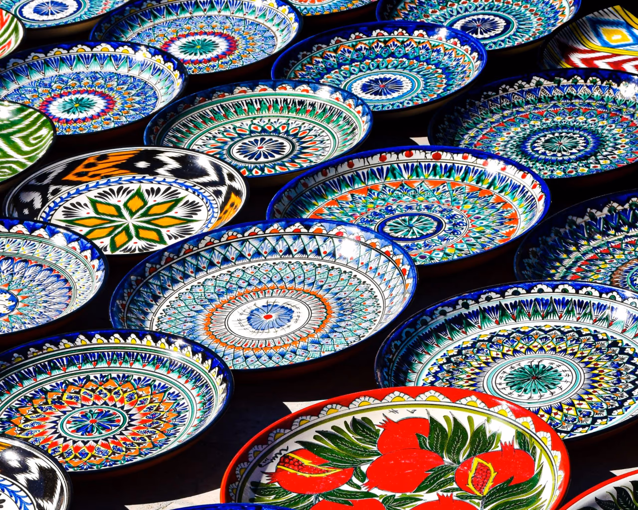 Vibrant hand-painted Uzbek ceramic plates with intricate geometric and floral patterns in Bukhara
