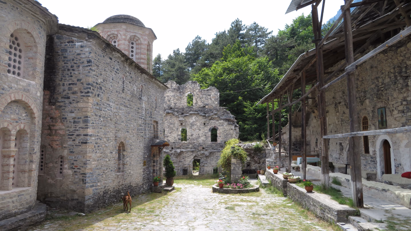 Historic Agios Dionysios Monastery ruins in the Enippeus Gorge, Mount Olympus, Greece, surrounded by lush forest.
